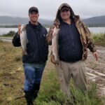photo of two people with fish they caught